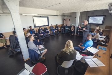 Das Bild zeigt Personen, die sich in einem Stuhlkreis austauschen.