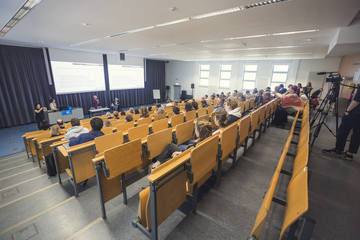 Das Bild zeigt Stuhlreihen in einem Hörsaal.