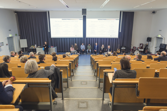 Das Bild zeigt Stuhlreihen in einem Hörsaal.