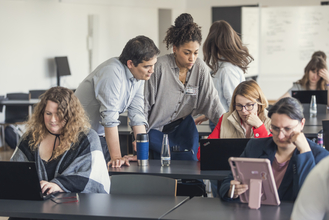 Eine Gruppe von Personen schauen gemeinsam auf einen Laptop.